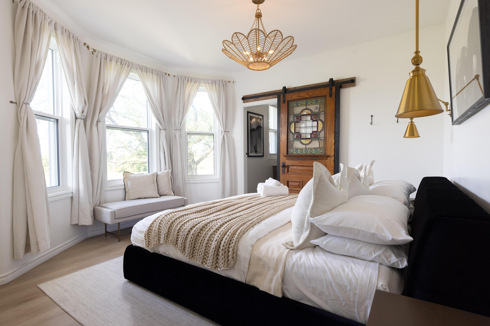 Master bedroom in The Ranch House at Sorella 1881 — luxury bed with gold chandelier and bay windows