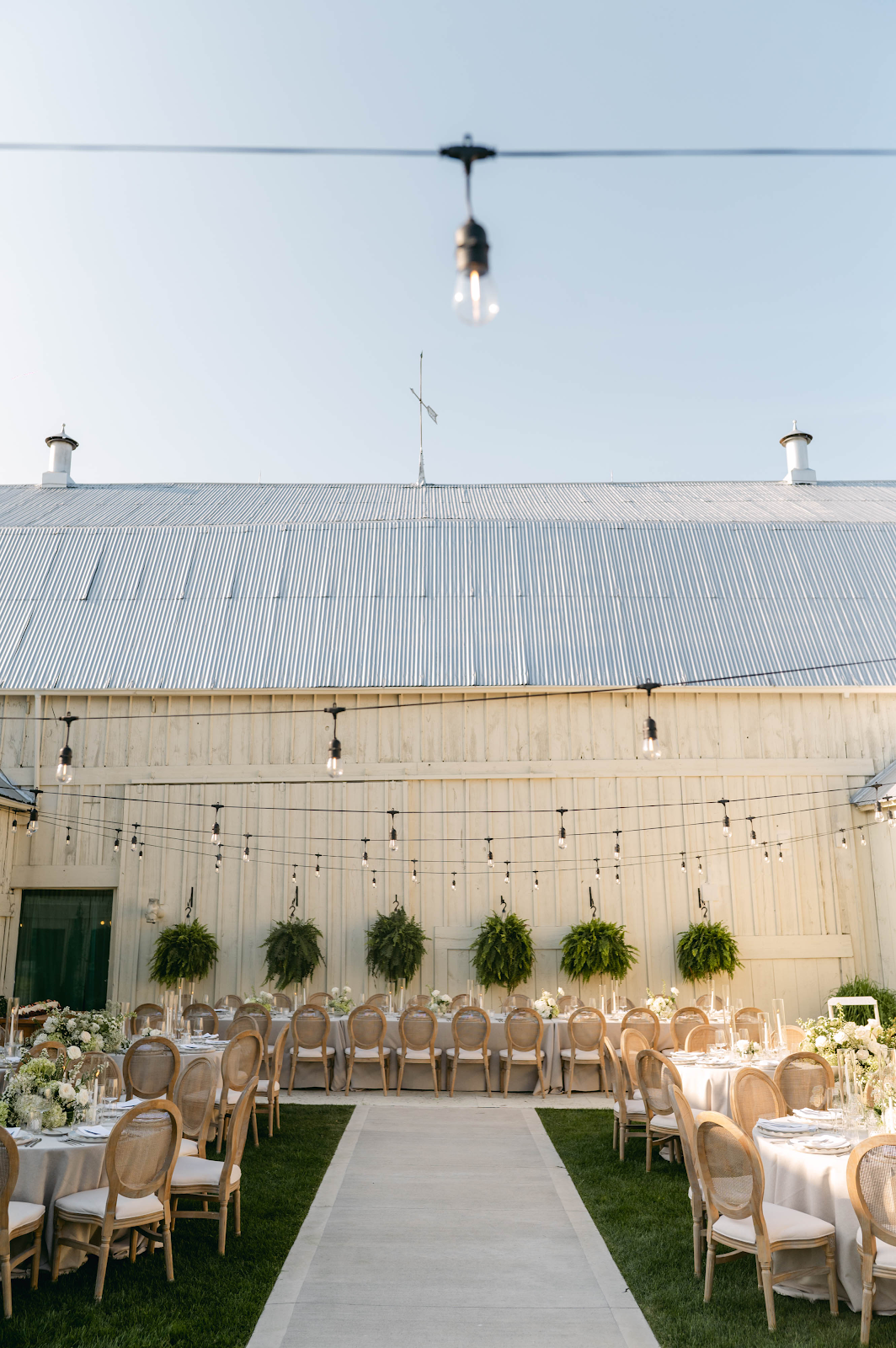 Al fresco courtyard dinner reception at Sorella 1881 with string lights and barn backdrop